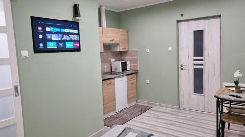 a kitchen with a flat screen tv on the wall at Belvárosi Pihenőház in Békéscsaba