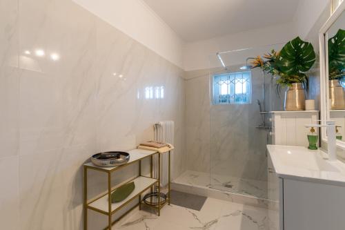 a white bathroom with a shower and a sink at Ioanna's Hellenic Hospitality in Athens