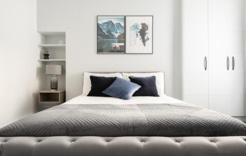 um quarto branco com uma cama com almofadas azuis em Stunning and Spacious 4 Bed Apr next to BrickLane em Londres