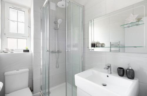 uma casa de banho branca com um lavatório e um chuveiro em Stunning and Spacious 4 Bed Apr next to BrickLane em Londres