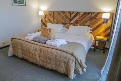 - une chambre avec un grand lit et une tête de lit en bois dans l'établissement Hôtel Restaurant Atrachjata, à Aléria