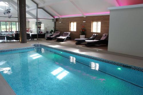 a swimming pool in a building with chairs and tables at The Chalet in Radstock