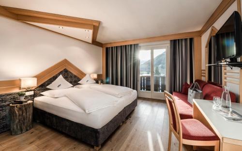 a hotel room with a bed and a table and chairs at Ferien & Wellnesshotel Windschar in Brunico