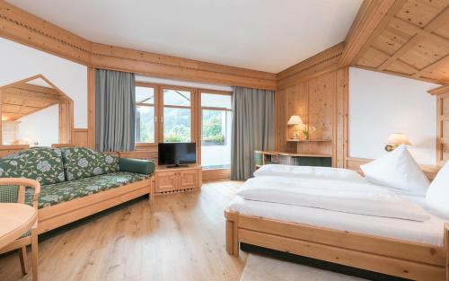 a hotel room with two beds and a couch at Ferien & Wellnesshotel Windschar in Brunico