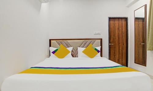 a bedroom with a white bed with yellow and colorful pillows at Itsy Hotels Phoenix in Indore