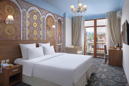 Un dormitorio con una gran cama blanca y un balcón. en Garuda Boutique Hotel, en Sukhum