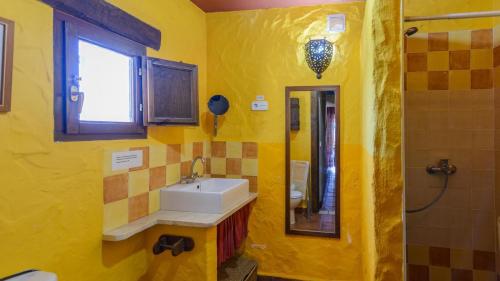 een gele badkamer met een wastafel en een spiegel bij Casa del Pino Casarabonela by Ruralidays in Casarabonela