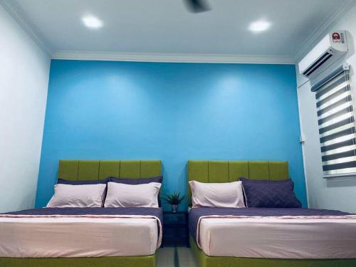 two beds in a room with a blue wall at The Green Semenyih Homestay Family Suites 14 PAX in Semenyih