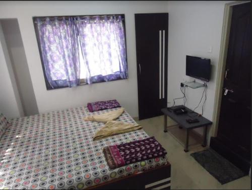 a bedroom with a bed and a table and a window at Hotel Vijay by WB Inn in Kānpur