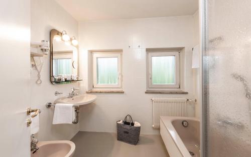 a white bathroom with a sink and a bath tub at Ferien & Wellnesshotel Windschar in Brunico
