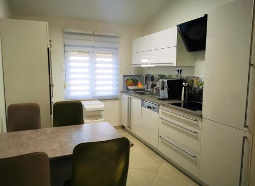 kuchnia z białymi szafkami, stołem i krzesłami w obiekcie Apartments Petar Pan w Fažanie
