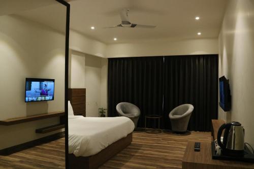 a hotel room with a bed and two chairs and a tv at Hotel The Sawai in Jaipur
