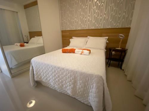 1 dormitorio con 1 cama blanca grande y espejo en Exclusivo Quarto e Sala na Praia da Barra em Salvador - Concept House Brazil, en Salvador
