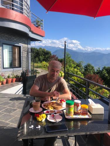 Un uomo seduto a un tavolo con un piatto di cibo di Hotel Pristine Himalaya a Pokhara