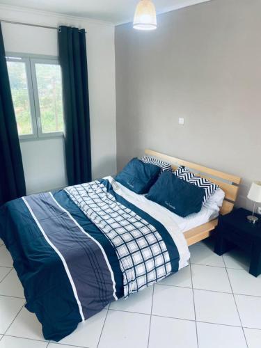 a bedroom with a bed with blue and white blankets and pillows at Résidence Le Vieux Lyon Après collège père monti in Yaoundé