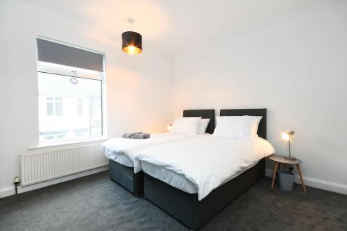 a bedroom with a large bed with white sheets and a window at Modern Town House in Chesterfield & The Peaks in Newbold