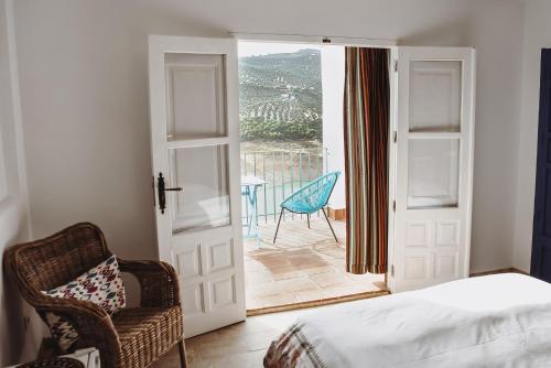 um quarto com uma cama, uma cadeira e uma varanda em Lake room 2 em Iznájar