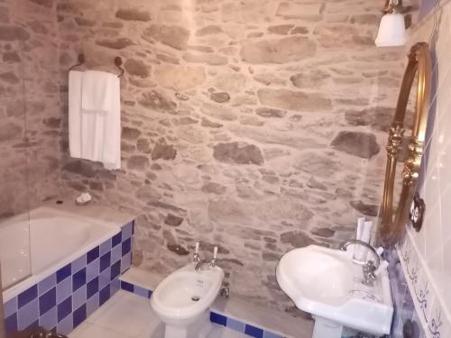 een badkamer met een wastafel, een toilet en een bad bij Casa Almoina in Viveiro