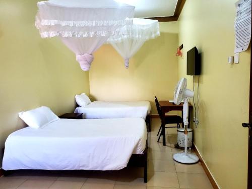 a room with two beds and a desk with a phone at The Sparrow Hotels in Soroti