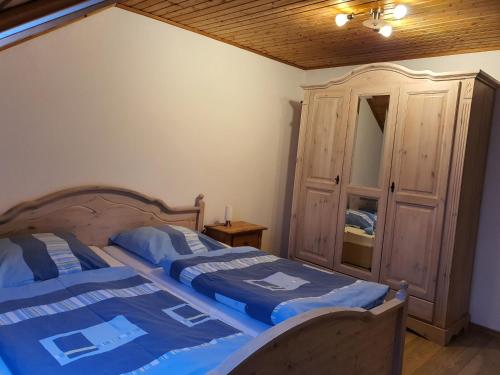 a bedroom with a bed with a wooden headboard and a cabinet at Kleberhof - Urlaub auf dem Bauernhof in Eslarn