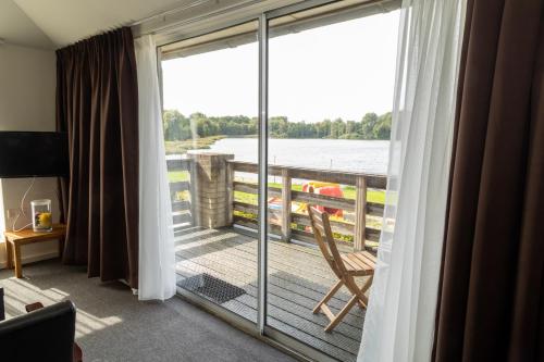 a room with a balcony with a view of the water at De Rozenborg in Scharmer