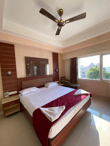 1 dormitorio con 1 cama grande y ventilador de techo en Maya Residency, en Tiruchchirāppalli