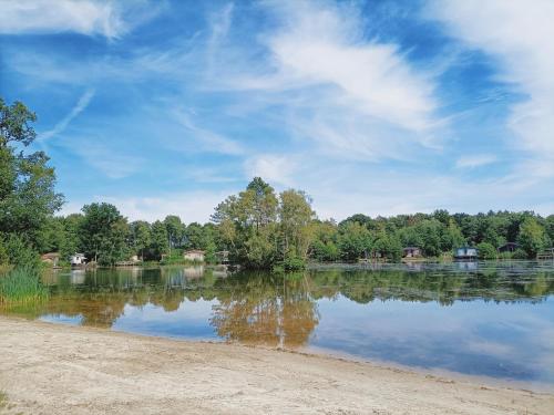 a view of a lake with trees in the background at 4p chalet TOLVE met 4 fietsen vlakbij natuurgebieden Drents Friese Wold, Fochteloërveen en gevangenisdorp Veenhuizen in Oosterwolde