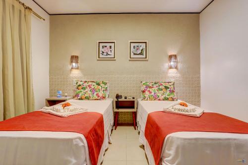 a hotel room with two beds with red sheets at Pousada Praia Bela in Ilhéus