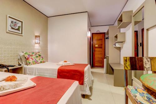 a hotel room with two beds and a table at Pousada Praia Bela in Ilhéus