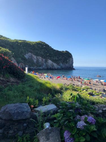 a group of people on a beach near the ocean at Alojamento CASA DA FIGUEIRA in Ponta Delgada