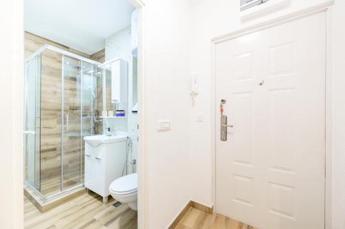 een witte badkamer met een toilet en een douche bij Apartment UNA Alipasino with two bedrooms in Sarajevo