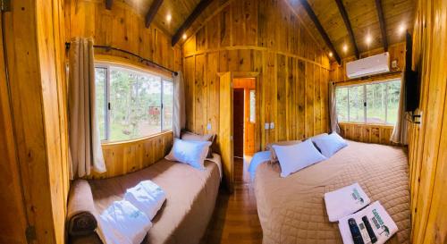 a bedroom with two beds in a wooden cabin at Cabanas Imbuia in Cambará