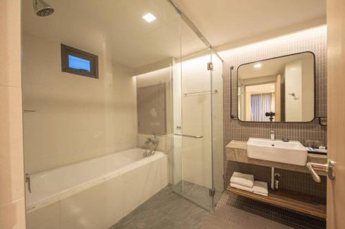 a bathroom with a tub and a sink and a mirror at Bella B Hotel in Nonthaburi