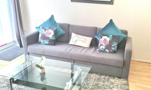 uma sala de estar com um sofá com almofadas e uma mesa de vidro em Parkway em London Colney