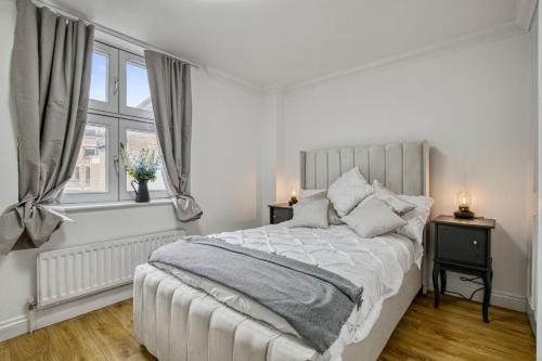1 dormitorio blanco con 1 cama y 2 ventanas en 2-Bed 2-Bathroom Mayfair - Maddox St en Londres