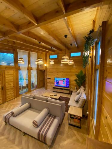 a living room with a couch and a tv at كوخ آفيري Aviary Hut in AlUla