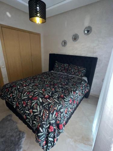 Un dormitorio con una cama con un edredón negro. en Magnifique Appartement balnéaire à Bouznika avec piscine, en Bouznika