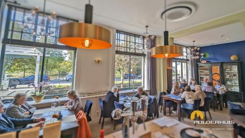 a group of people sitting at tables in a restaurant at Polderhuis Bed & Breakfast in Bergschenhoek