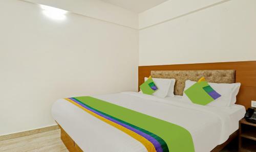 a bedroom with a white bed with a colorful blanket at Treebo Celebrity Hotels And Suites in Bengaluru