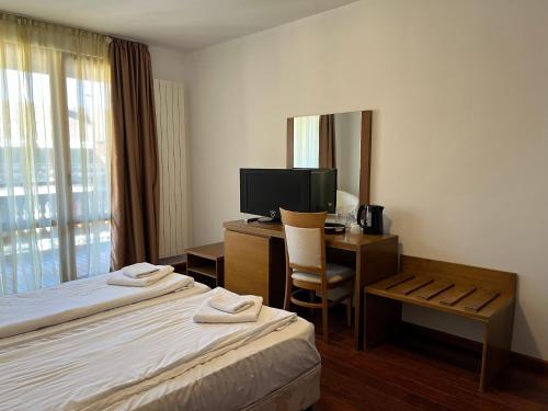 una camera d'albergo con due letti, una scrivania e una televisione di Ski & Relax Apartments in Bellevue Residence a Bansko