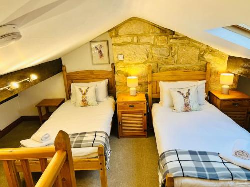a bedroom with two beds and a stone wall at Otley Cottage in Otley