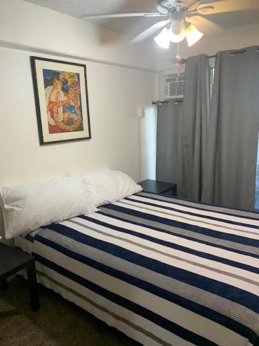 a bedroom with a striped bed with a ceiling fan at Ocean and Mountain View Condo - Free Reserved Parking in Honolulu
