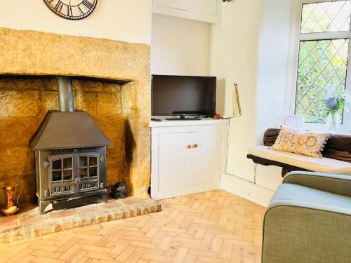 a living room with a fireplace and a tv at Otley Cottage in Otley