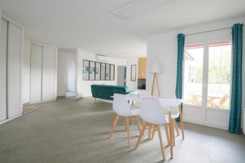 une salle à manger avec une table et des chaises blanches dans l'établissement LE CARRELET DE L'ESTUAIRE , Jolie MAISON ENTIÈRE à 9 min DE LA CITADELLE, à Saint-Seurin-de-Cursac
