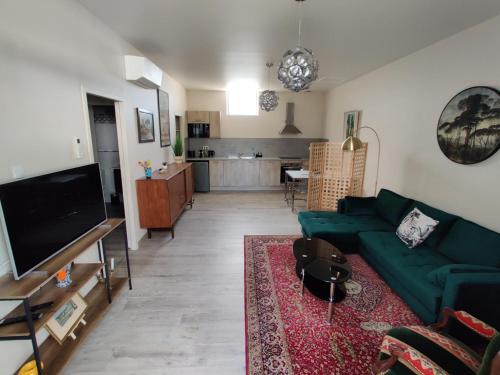 un salon avec un canapé vert et une cuisine dans l'établissement Gîte Pavillon Flavia, à Vaison-la-Romaine