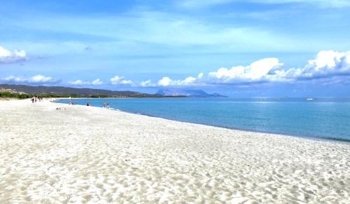 een wit strand waar mensen langs het water lopen bij Graziosi appartamenti a Budoni con aria condizionata a soli 300 mt dal mare in Budoni