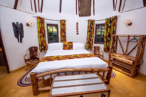 a bedroom with a bed in a room with windows at Etana Cottage in Kakamega