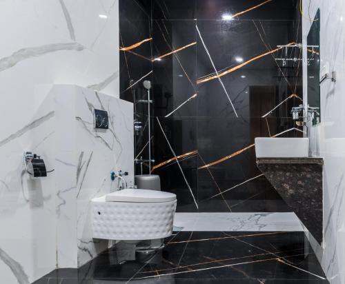 a black and white bathroom with a toilet and a sink at Meridian Hotel & Banquet in Surat
