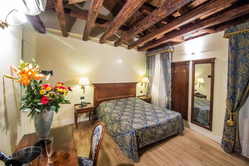 ein Schlafzimmer mit einem Bett und einem Tisch mit einer Blumenvase in der Unterkunft B&B Le Marie in Venedig