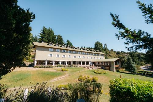 duży budynek na wzgórzu z ogródkiem w obiekcie Gran Hotel Panamericano w mieście Bariloche